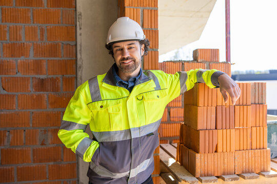 Construction worker standing beside brick stack indoors