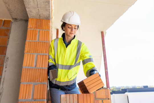 Female construction worker placing brick with trowel