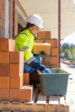 Female builder taking cement mortar with trowel from container