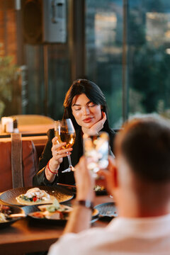 Young woman holding a wine glass during a pleasant dinner date inside a restaurant at night time