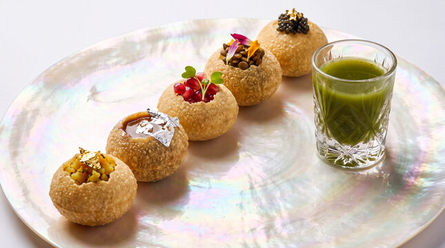 Gourmet pani puri platter with diverse toppings and spiced water served on an iridescent shell plate