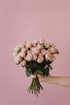 Close-Up of Hand Holding Romantic Rose Bouquet in Studio Light. Greeting card, wedding invitation, product mockup
