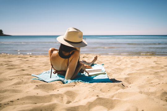 Woman reading on beach towel by the sea