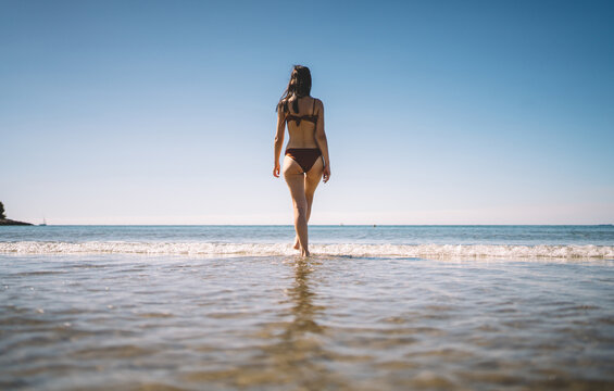 Rear view of woman entering shallow sea water
