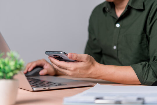 Person Using Smartphone and Laptop in Digital Workspace