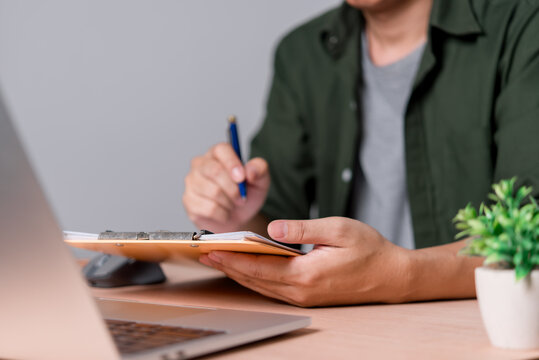 Person Writing Documents at Laptop Office Workspace