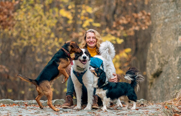 Fototapeta premium happy woman with dogs playing outdoors in autumn forest