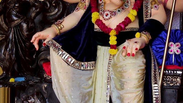 Ganesha idol torso showing blessing hand golden bangles and marigold garlands Ganesh Chaturthi festival India