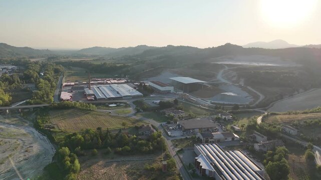 Industrial brickworks and adjacent quarry complex surrounded by cultivated fields, access roads, extraction tracks, processing buildings and rolling hills.