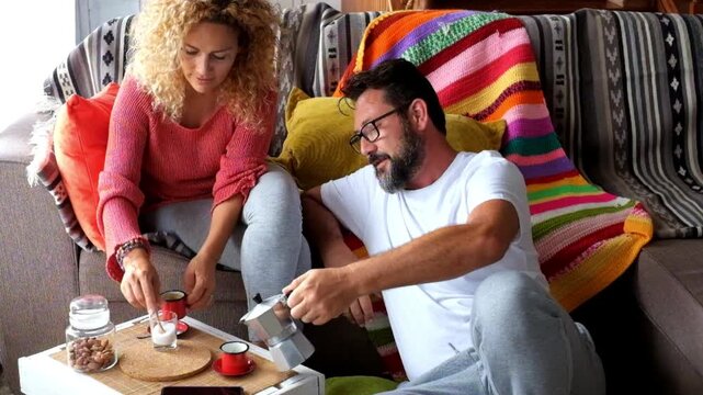 A happy couple enjoys a relaxing coffee break at home, cherishing a tranquil moment together in their cozy living room, demonstrating authentic domestic bliss.