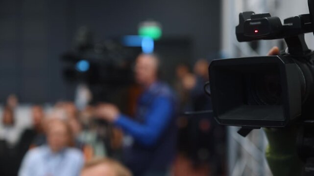 Professional video camera recording and broadcasting a business conference. Media production, live event coverage and professional video streaming concept.