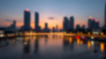 Fototapeta premium Blurred city skyline at dusk with reflections in water.