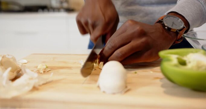 Lifestyle videos indoor of people doing activities at home, chopping garlic on board, person prepari