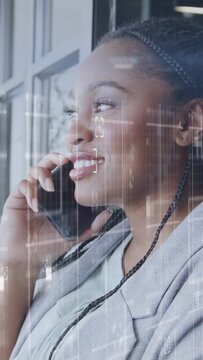 Vertical video: Businesswoman taking call at window, speaking and smiling while light lines overlay