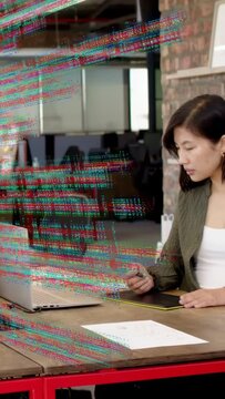 Vertical video: Designer editing, tapping pen on laptop, watching code overlay fade while smiling