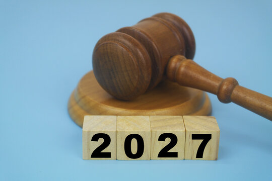 Wooden judge gavel and numbers 2027 on cubes on blue background. Legal system and laws in 2027 concept.	