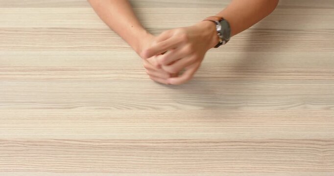 Close up of people talking to the camera, hands resting on wooden table, person wearing watch and cl