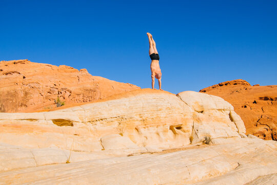 White person doing handstand on desert rock formation