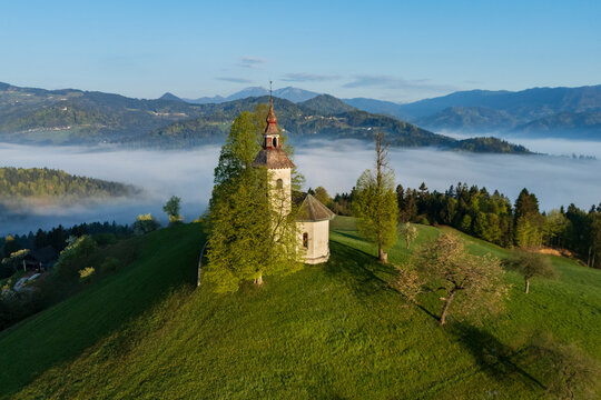 Church on hilltop at Sunrise with fog and mountains in skofje loka