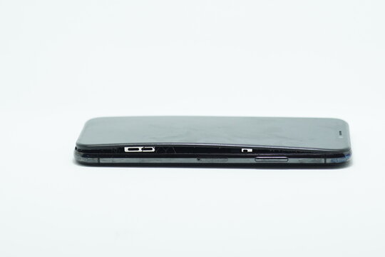 Damaged mobile phone with expanded swollen battery lifting screen isolated on white background