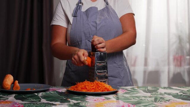 Close up of preparing fresh carrot with kitchen grater for homemade recipes using natural ingredients during healthy food cooking process. High quality 4k footage