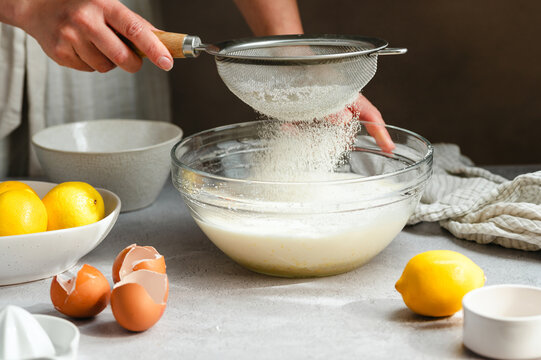 Sifting flour into lemon cake batter, process of home baking