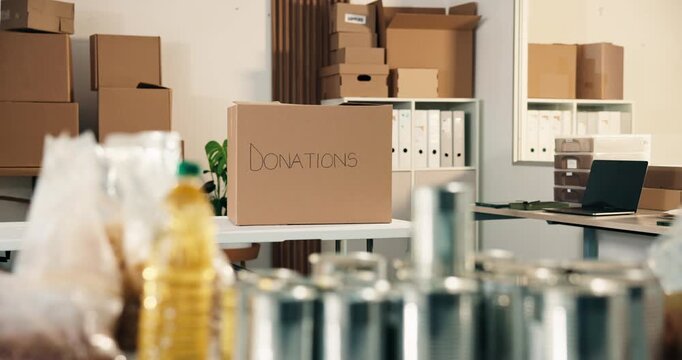 Office, donations and box with groceries for charity, canned food and non profit of poverty relief. Empty, workplace or supplies in cardboard for collection, pantry staple and aid package for welfare