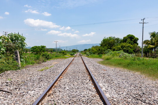 Railroad Tracks Crossing Green Countryside in Colima Mexico Toward Distant Mountains
