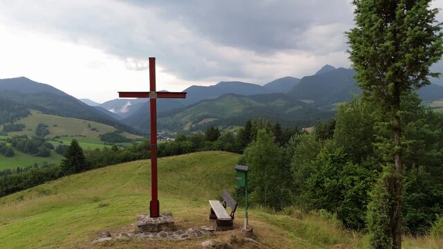 Side movement trucking shot of a wooden Christian cross on a mountain hill before storm