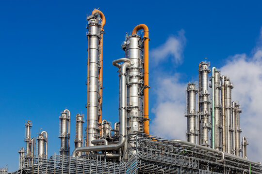 Pipes, pipelines and cooling towers at an industrial oil refinery and power station as part of the energy production infrastructure.