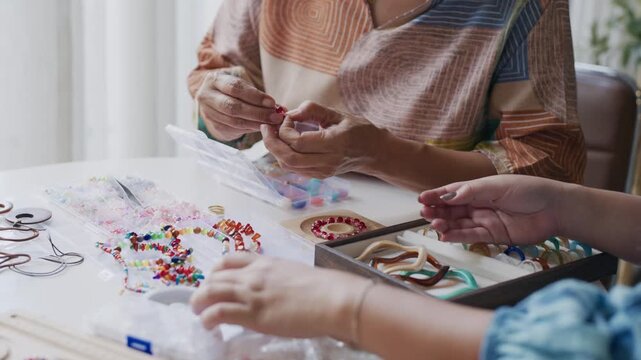 asian people making stringing colorful beads in creative craft workshop