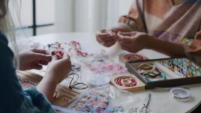 asian people making stringing colorful beads in creative craft workshop