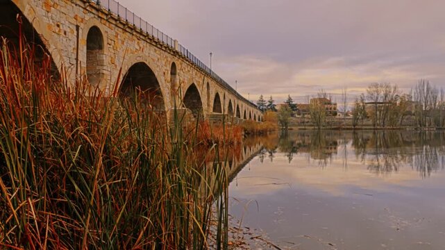 Masonry Pointed arch Stone bridge (Puente de Piedra) across the river Duero in Zamora, Castile-Leon, Spain. Reflection in the water.