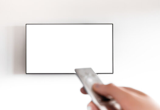 Hand holding remote control to switch channels on wall television. Modern smart tv screen mockup
