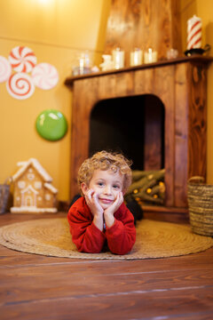 Young boy smiling, lying on rug near decorated fireplace, enjoying Christmas holiday season at home
