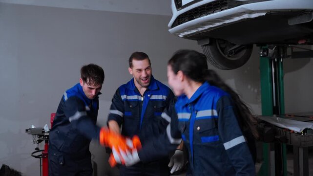 Automotive Mechanics Celebrating Successful Vehicle Repair and Teamwork. Group of automotive mechanics celebrating together after completing a vehicle repair task in a professional workshop. Concept o