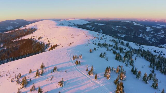An extraordinary valley with hills and mountains covered with fir forests against the backdrop of a bright pink sunset