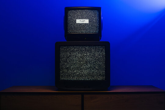 Vintage CRT televisions displaying static noise and no signal under blue lighting