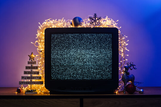 Vintage CRT television with static screen, glowing lights and festive holiday decorations