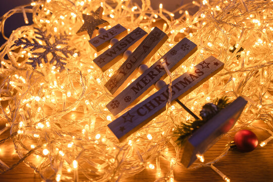Wooden tree ornament with Merry Christmas message surrounded by glowing warm fairy lights
