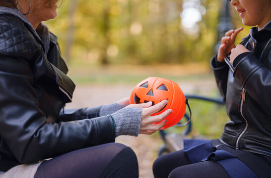 Mother and daughter prepare for Halloween walk in autumn park, wearing witch hats and holding jack o lantern, surrounded by colorful foliage in Zagreb in Croatia sunny October day.
