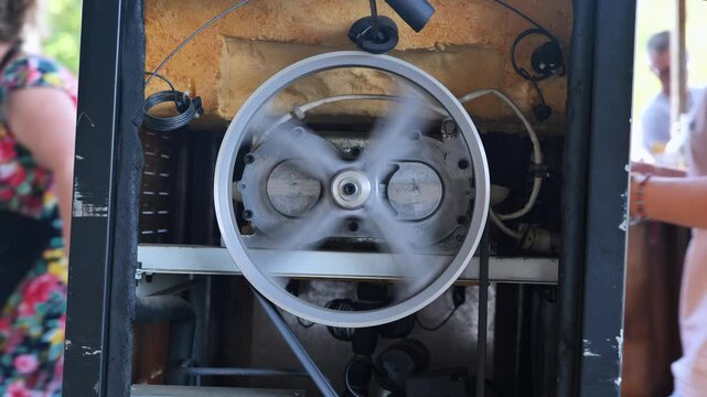 Industrial machine working, showing a spinning pulley and belt creating movement