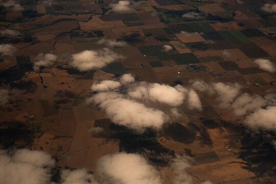 Aerial view of agricultural patchwork fields with scattered clouds from above