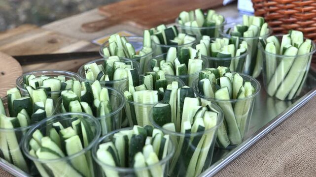 Fresh cucumber sticks in individual cups on a tray, ready for healthy snacking