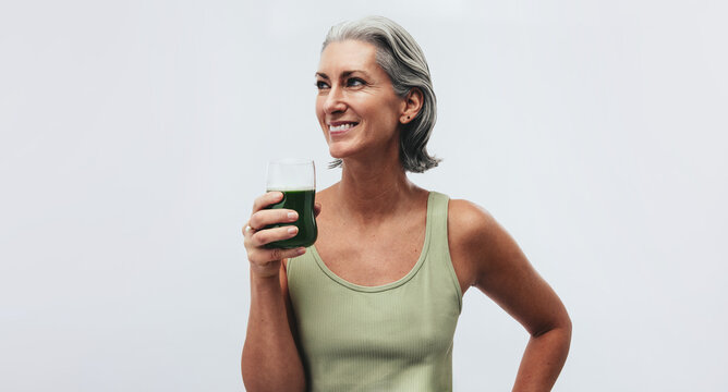 Mature woman drinking juice and smiling