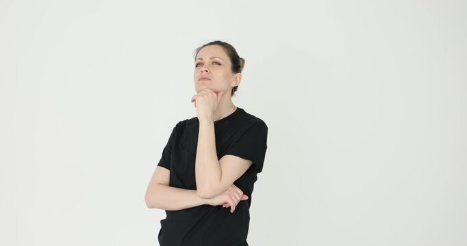 Pensive woman rests hand under chin as moves through room. Female with hair bun searches for sensible solution to important problem. Slow motion