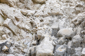 Close-up of rough pale limestone and gray stone fragments forming a natural rocky texture background with uneven cracks and weathered surfaces. © Maria