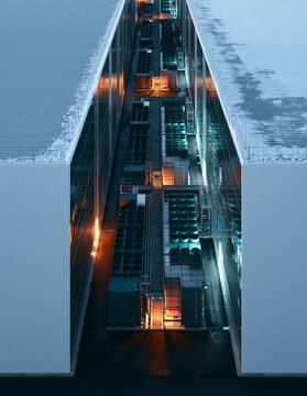 Data center cooling units from above, rows of rooftop chiller fans in the canyon between two hyperscale server halls, vertical aerial of a data center cooling system at blue hour