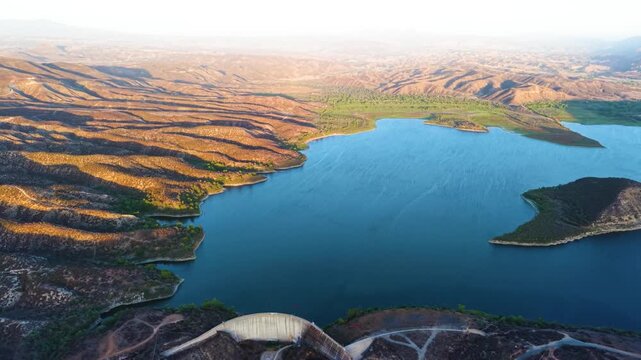 Vail Lake and surrounding ridges illuminated by warm evening light with the dam below, aerial medium overview at golden hour