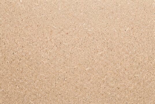 Particle board pressed wood surface texture. Detailed overhead view of a composite chipboard panel. Industrial material and carpentry background